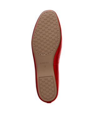 Red patent leather ballet flat with delicate bow detail, featuring a glossy finish. Bottom view